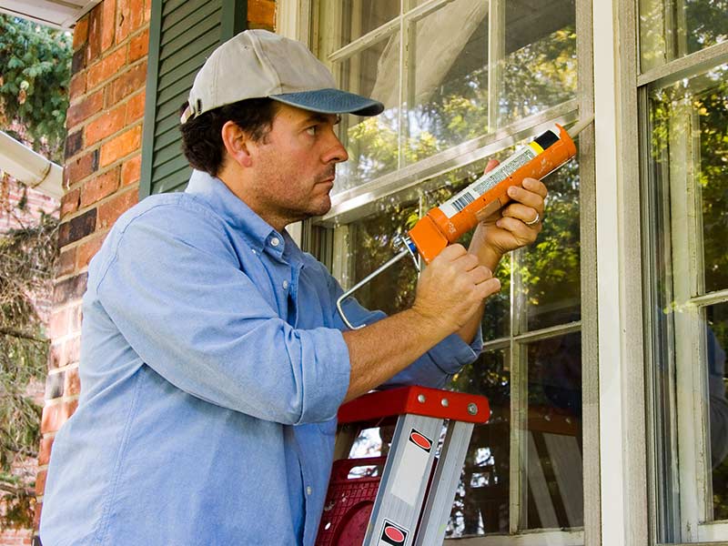 A man caulking a window