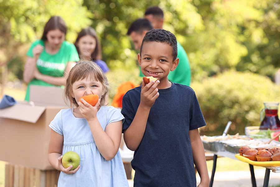 Children enjoying fruit at an outdoor community gathering