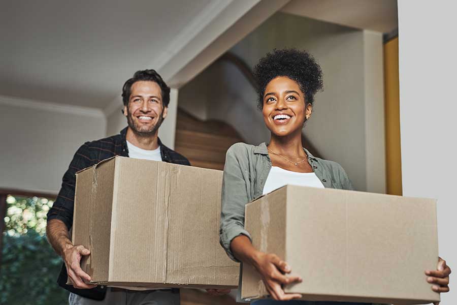 Couple carrying moving boxes into their new home